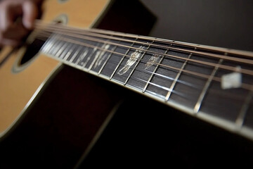 Fototapeta premium Close-up of fingers plucking guitar strings during an evening jam session in a cozy setting