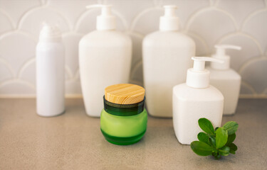A close-up of a jar of green glass cream with a wooden lid and a twig with leaves