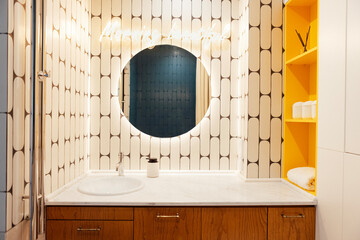 Modern stylish bathroom interior. Close-up of marble countertop with sink and large round...