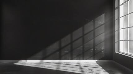 Obraz premium A black and white image of an empty room with a large window that is casting light onto the floor.