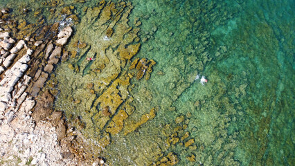 Mediterranean, Tropical Crystal Clear Water, Rocky Seabed and Underwater Stones. Golden underwater stones and natural patterns on the scene. Top down aerial perspective shows coastal geology.