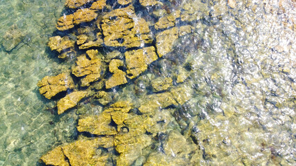 Mediterranean, Tropical Crystal Clear Water, Rocky Seabed and Underwater Stones. Golden underwater stones and natural patterns on the scene. Top down aerial perspective shows coastal geology.
