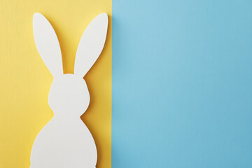Obraz premium A minimalistic white bunny silhouette with subtle gold details, standing against a textured sunny yellow and chambray blue gradient background.
