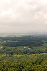 Fototapeta premium Lush Green Valley North Korea With Dense Forests, Rolling Hills, And Agricultural Fields Under A Cloudy Sky