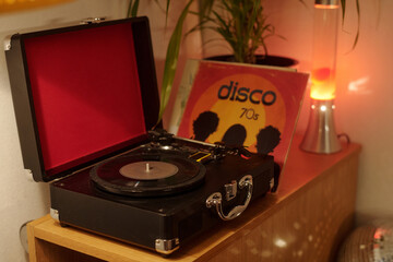 Classic turntable playing a vintage vinyl record with a disco album in background, creating...