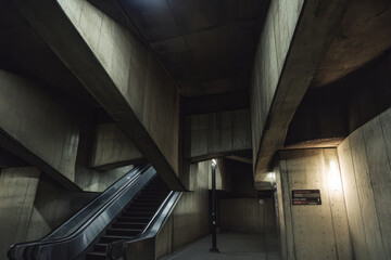 A brutalist underground metro station with heavy concrete beams, dim lighting, and raw industrial aesthetics.