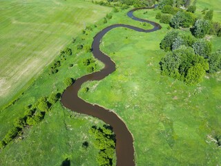 Aerial view of a river winding through a verdant landscape of forest and fields - Vue aérienne...