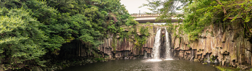 Stunning Twin Waterfall Flowing Over Volcanic Basalt Columns Amidst Lush Greenery in Jeju Island