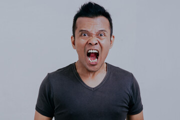 Close-up portrait of Crazy Asian man screaming loudly isolated on white background.