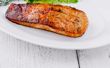 Grilled salmon fillet lying on a white plate