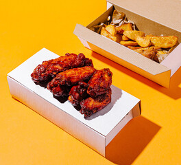 Delicious chicken wings and golden fries served in takeout boxes