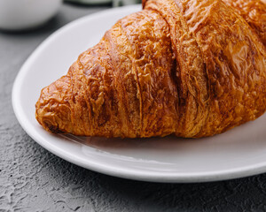 Golden brown croissant on white plate