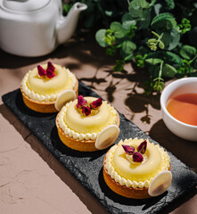 Sweet lemon tarts garnished with rose petals on a serving plate