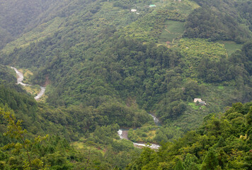 Lush Green Valley with Winding River and Isolated Farmhouses Nestled Amid Taiwan’s Rugged Mountain Landscape