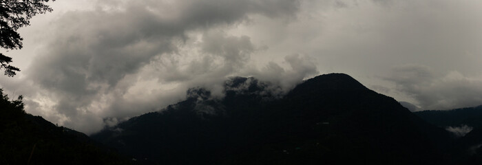 Dark Storm Clouds Swirling Around Towering Mountain Peaks Creating a Dramatic and Mysterious Atmosphere in Taiwan
