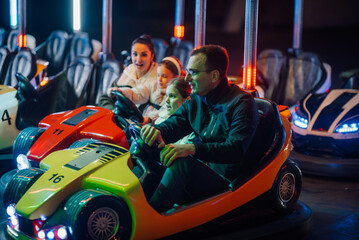 Family having fun driving bumper cars at amusement park