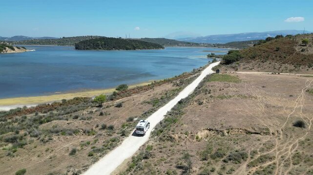 Camper van, RV or motor home is driving on gravel road from&nbsp;Zvernec beach or Dalan beach near Vlore, Albania. Off Road driving a camper motorhome is exploring wild nature.