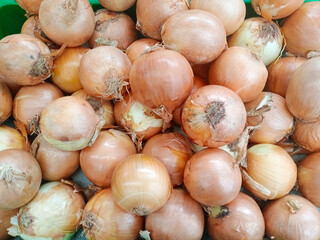 Close-up showing a bunch of freshly harvested shallots. These shallots have light brown skin with a purple tinge, and some still have their roots attached.