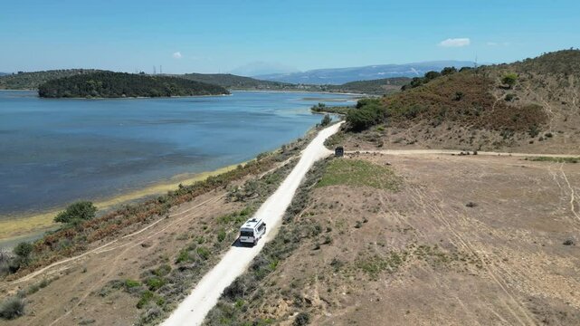 Camper van, RV or motor home is driving on gravel road from&nbsp;Zvernec beach or Dalan beach near Vlore, Albania. Off Road driving a camper motorhome is exploring wild nature.