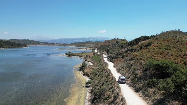 Camper van, RV or motor home is driving on gravel road from&nbsp;Zvernec beach or Dalan beach near Vlore, Albania. Off Road driving a camper motorhome is exploring wild nature.