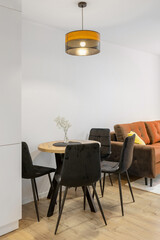 Vertical image of a small dining room with a round table and comfortable velvet chairs, showcasing an elegant and cozy atmosphere