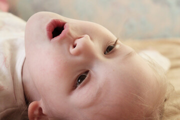 portrait of a baby. little girl is singing with an opened mouth sound "o"