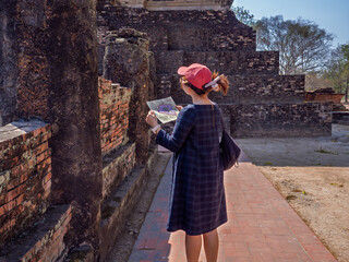 Thai female tourist with map Studying travel information At Sukhothai Historical Park, Thailand
