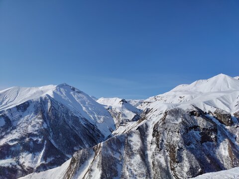 Beautiful view of the snow-capped peaks of the Caucasus Mountains and blue sky from the Russia-Georgia Friendship Monument on the Georgian Military Road in Gudauri - Powered by Adobe