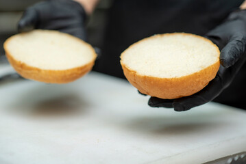 Chef in black gloves preparing gourmet burgers with fresh vegetables and sauce and cutlet in fast food restaurant