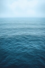 Fototapeta premium Calm ocean waves gently roll under a cloudy sky at dawn in a tranquil coastal environment