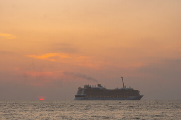 Sunset on a luxury cruise ship turns the sky orange and pink, creating a stunning view. Experience...