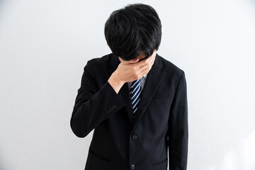 悩み落ち込むスーツを着た男性