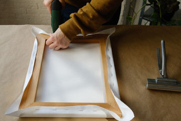 Framer stretching canvas on wooden stretcher bars. 