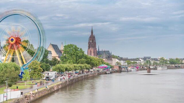 Aerial hyperlapse of pleasure boats on the Rhine Main, framed by the spire of Kaiserdom St. Bartholomaus. Eiserner Steg bridge and Ferris wheel add vibrancy to Frankfurt's scenic waterfront timelapse