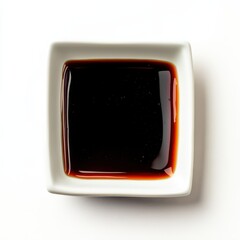 Overhead shot of dark soy sauce in a square white dish.