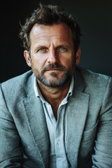 Obraz premium Handsome adult man with beard and intense gaze posing in casual attire against a dark background