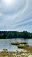View of the lake with forest and blue sky with clouds