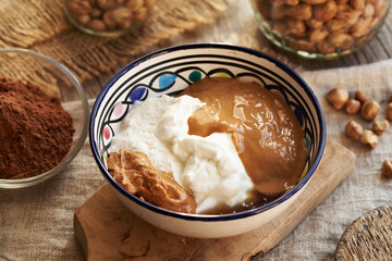 Greek yogurt, nut butter and maple syrup in a bowl - ingredients for alternative healthy sweets