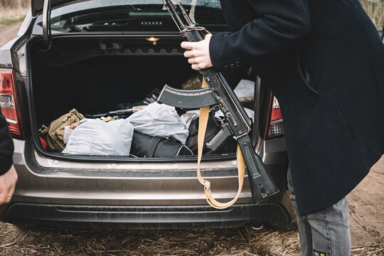 Arms trafficking. different rifles. clandestine sale of weapons. illegal deal to sell weapons. A man pulls an assault rifle out of a car. The concept of arms smuggling.