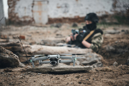 UAV operator with a remote control sitting in a trench. concept of unmanned technologies in modern warfare. bombing reconnaissance drone. A soldier controls a drone. the remote control is in hands.