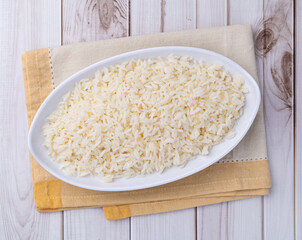 Cooked white rice in a plate over wooden table