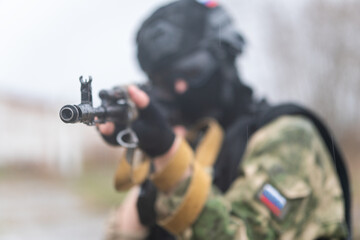 Fototapeta premium Soldier or militiaman in camouflage with assault rifle fighting in ruins. A special forces soldier storms a destroyed building. concept of war and military anti-terrorist exercises.