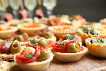Many different tasty canapes on wooden board, closeup