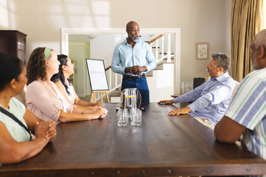 Senior man leading meeting with diverse group at home, discussing plans
