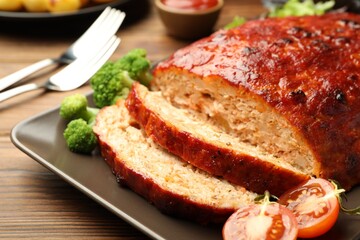 Delicious turkey meatloaf with vegetables served on wooden table, closeup