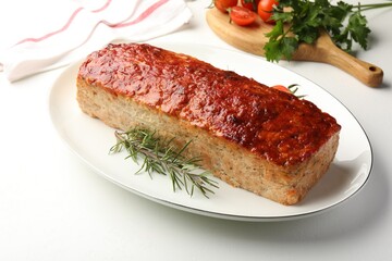 Delicious baked turkey meatloaf, rosemary, cherry tomatoes and parsley on white table, closeup