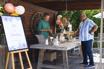 Decorating outdoor party table, two senior men preparing for birthday celebration