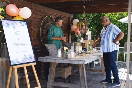 Decorating outdoor party table, two senior men preparing for birthday celebration - Powered by Adobe