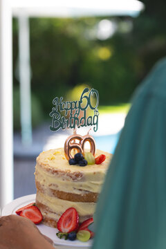 Celebrating 60th birthday with delicious cake topped with fresh fruits outdoors