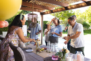 Diverse senior friends enjoying outdoor celebration, sharing laughter and drinks by poolside